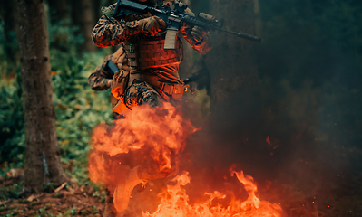 Image showing Soldier in Action at Night in the Forest Area. Night Time Military Mission jumping over fire