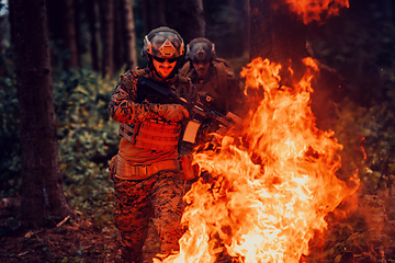 Image showing Soldier in Action at Night in the Forest Area. Night Time Military Mission jumping over fire