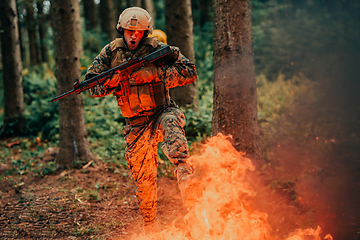 Image showing Soldier in Action at Night in the Forest Area. Night Time Military Mission jumping over fire