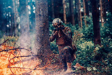 Image showing A soldier fights in a warforest area surrounded by fire