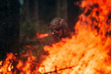 Image showing A soldier fights in a warforest area surrounded by fire