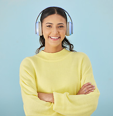 Image showing Portrait of woman, headphones and smile in studio listening to podcast, mobile app and streaming radio site. Sound, music media subscription and happy girl with arms crossed on blue background space.