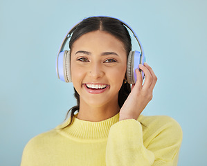 Image showing Portrait of happy woman, headphones and mockup in studio listening to podcast, mobile app and streaming radio site. Smile, music media subscription and sound, face of girl on blue background space.