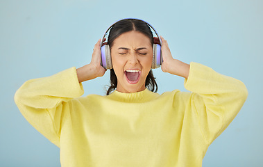 Image showing Music, screaming and headphones with a woman in studio on a gray background while streaming audio. Radio, shouting or expression and an angry young female person listening to sound or loud noise