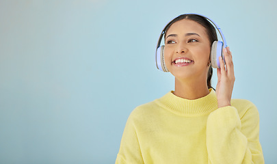 Image showing Happy woman, headphones and banner mockup in studio listening to podcast, app and streaming radio site. Smile, music media subscription and sound, face of girl with audio on blue background space.