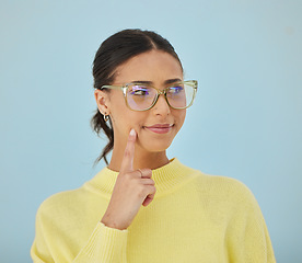 Image showing Woman, smile and glasses in studio thinking, problem solving style and vision on blue background. Ideas, eyewear and happy model brainstorming with hand on face in cool fashion, mindfulness and gen z