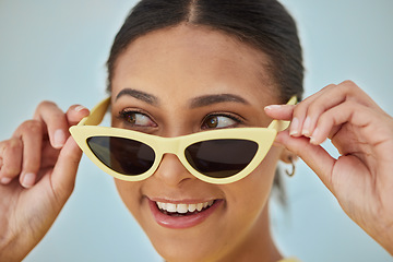 Image showing Smile, sunglasses and young woman in a studio with a casual, stylish and cool eyewear. Happy, excited and female model with trendy gen z style and fashion accessory isolated by a blue background.