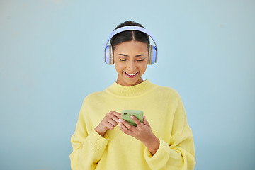 Image showing Woman with phone, headphones and mockup in studio for social media post, mobile app and streaming radio site. Smile, music media subscription and happy girl with cellphone on blue background space.