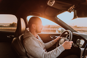 Image showing A man with a sunglasses driving a car at sunset. The concept of car travel