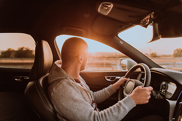 Image showing A man with a sunglasses driving a car at sunset. The concept of car travel