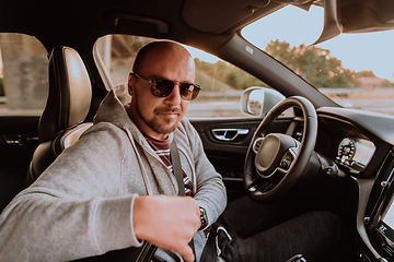 Image showing A man with a sunglasses driving a car at sunset. The concept of car travel