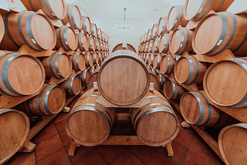 Image showing Wine or cognac barrels in the cellar of the winery, Wooden wine barrels in perspective. Wine vaults.Vintage oak barrels of craft beer or brandy.