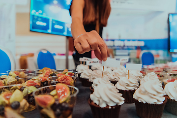 Image showing Business woman takes delicious food from the table while in the conference room