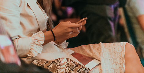 Image showing Close-up photo of a woman using a smartphone while sitting in a conference room