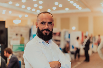 Image showing Portrait of a business man with a beard. In the background, a group of business people preparing for the start of the conference