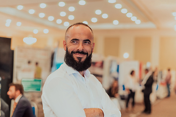 Image showing Portrait of a business man with a beard. In the background, a group of business people preparing for the start of the conference