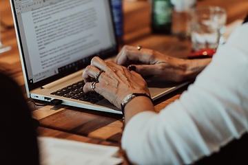 Image showing Close up photo of an elderly woman typing on a laptop at a seminar