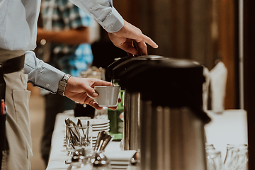 Image showing The waiter preparing coffee for hotel guests. Close up photo of service in modern hotels