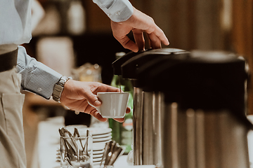 Image showing The waiter preparing coffee for hotel guests. Close up photo of service in modern hotels