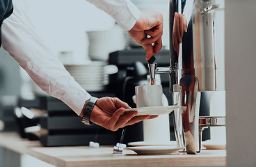 Image showing The waiter preparing coffee for hotel guests. Close up photo of service in modern hotels