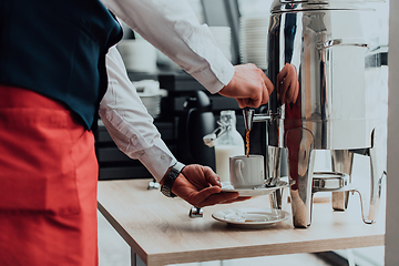 Image showing The waiter preparing coffee for hotel guests. Close up photo of service in modern hotels