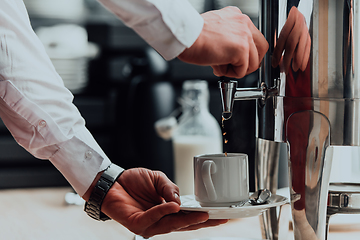 Image showing The waiter preparing coffee for hotel guests. Close up photo of service in modern hotels