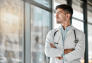 Image showing Doctor, thinking and arms crossed at the window in hospital, clinic and vision for the future of healthcare, medicine or surgery. Man, medical worker or intern with decision, choice and ideas