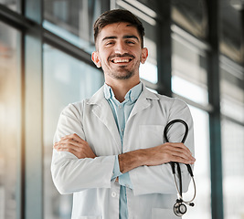 Image showing Crossed arms, happy and portrait of a male doctor with a stethoscope in a medical hospital. Confidence, smile and professional young man healthcare worker or surgeon with pride in medicare clinic.