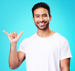 Image showing Man, smile and shaka in studio portrait with sign language, icon and youth by blue background. Indian student guy, fashion model and hand for call me, emoji and happy with gesture, symbol or contact