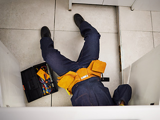 Image showing Kitchen, maintenance and repair with a plumber on the floor of a home to fix a leak, issue or problem. Plumbing, renovation and tools with a handyman or contractor working on a pipeline in a house