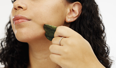Image showing Skincare, facial and beauty by woman using jade stone as self care isolated against a studio white background. Face, cosmetics and model doing detox massage or treatment for smooth skin