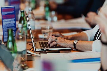 Image showing Close up photo of an elderly woman typing on a laptop at a seminar