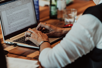 Image showing Close up photo of an elderly woman typing on a laptop at a seminar