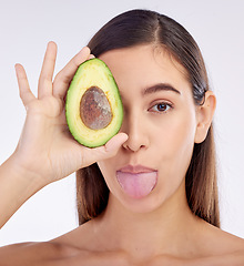 Image showing Face, skincare and woman with avocado, tongue out and isolated on a white background in studio. Portrait, beauty and natural model with fruit food for nutrition, healthy diet or omega 3 for wellness