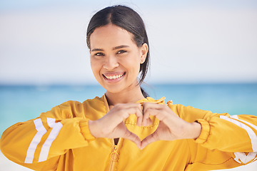 Image showing Happy woman, portrait and heart hands on beach for love, care or support in trust, health or romance. Outdoor female person with emoji, symbol or icon for like or wellness in peace, sign or emoticon