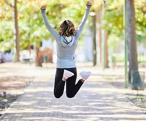 Image showing Fitness, jump and a woman outdoor for success at a park to celebrate win or achievement. Back of young female person on a road in nature excited about workout, running or training goals or freedom