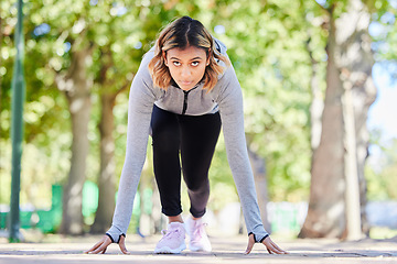 Image showing Run, exercise and a woman in start position outdoor at a park with commitment and focus on wellness. Young female person on a road in nature ready for workout, running or training for marathon