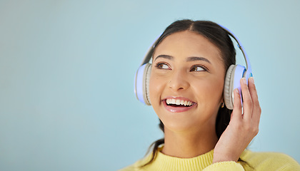 Image showing Woman with smile, headphones and mockup in studio thinking with technology on mobile app and streaming radio site. Podcast, music media subscription and happy girl with sound on blue background space