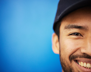 Image showing Studio, portrait and closeup on half of man in sports on blue background with advertising, mockup or space with athlete. Happy, face and smile with cricket or baseball cap and fitness or wellness