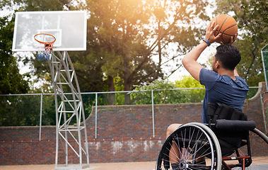 Image showing Sports, basketball and man in wheelchair shoot for playing competition, challenge and practice outdoors. Fitness, goals and male person with disability with ball for training, workout and exercise