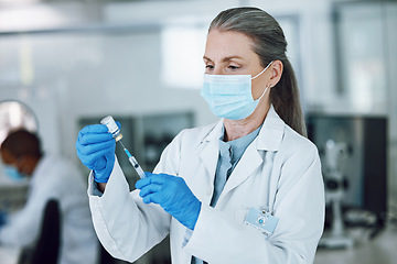 Image showing Woman doctor, scientist with mask, needle and vaccine bottle at hospital laboratory for covid research. Healthcare, medicine and medical professional with sample syringe for corona vaccination in lab