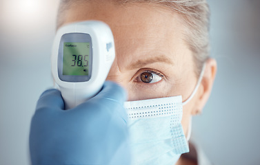 Image showing Woman in mask, hand of doctor and digital thermometer in hospital for covid, safety and healthcare consultation. Temperature test, corona and patient at clinic with medical professional for exam.