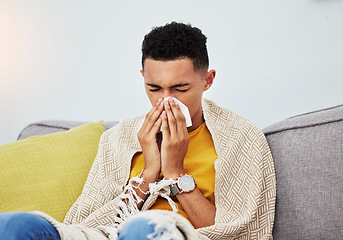 Image showing Sick, couch and man blowing nose with flu, cold and sinus fever in a home living room with a blanket on a sofa. Healthcare, sneeze and young person with difficult symptoms or medical problem in house