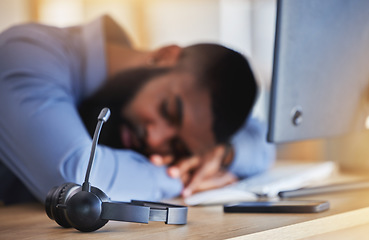 Image showing Call center, tired and man sleeping with microphone at desk for burnout, fatigue and low energy in telemarketing office. Closeup, stress and business consultant taking a nap at table in sales agency