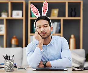 Image showing Tired, bunny ears and business man for Easter in office with decoration for celebration, event and party. Burnout, stress and Asian male person with fatigue at desk with rabbit headband for holiday