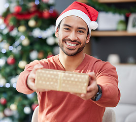 Image showing Christmas, portrait and asian man with gift giving in his home for celebration, fun and holiday with a smile. Happy, face and Japanese male with present box offer in a living room for festive event