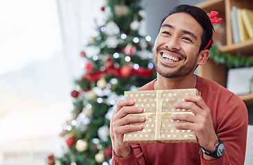 Image showing Christmas, surprise and asian man with gift in his home happy, excited and having fun celebrating holiday. Hand holding, box and Japanese male with present in a living room at December party or event