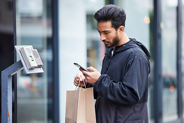 Image showing Courier man, paper bag and street with phone, typing and delivery app for service in supply chain job. Young logistics worker, package and thinking with smartphone, product or e commerce in metro cbd