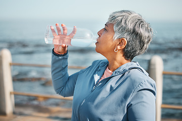 Image showing Outdoor, fitness or senior woman drinking water for hydration, wellness and thirsty on beach run, training or exercise. Bottle, runner or elderly person refresh with cold liquid on retirement workout