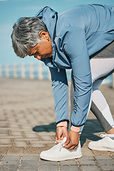 Image showing Fitness, beach and senior woman tie shoes ready for wellness, workout or training in the morning for health. Rest, sport and elderly person prepare for outdoor exercise by typing sneakers or running